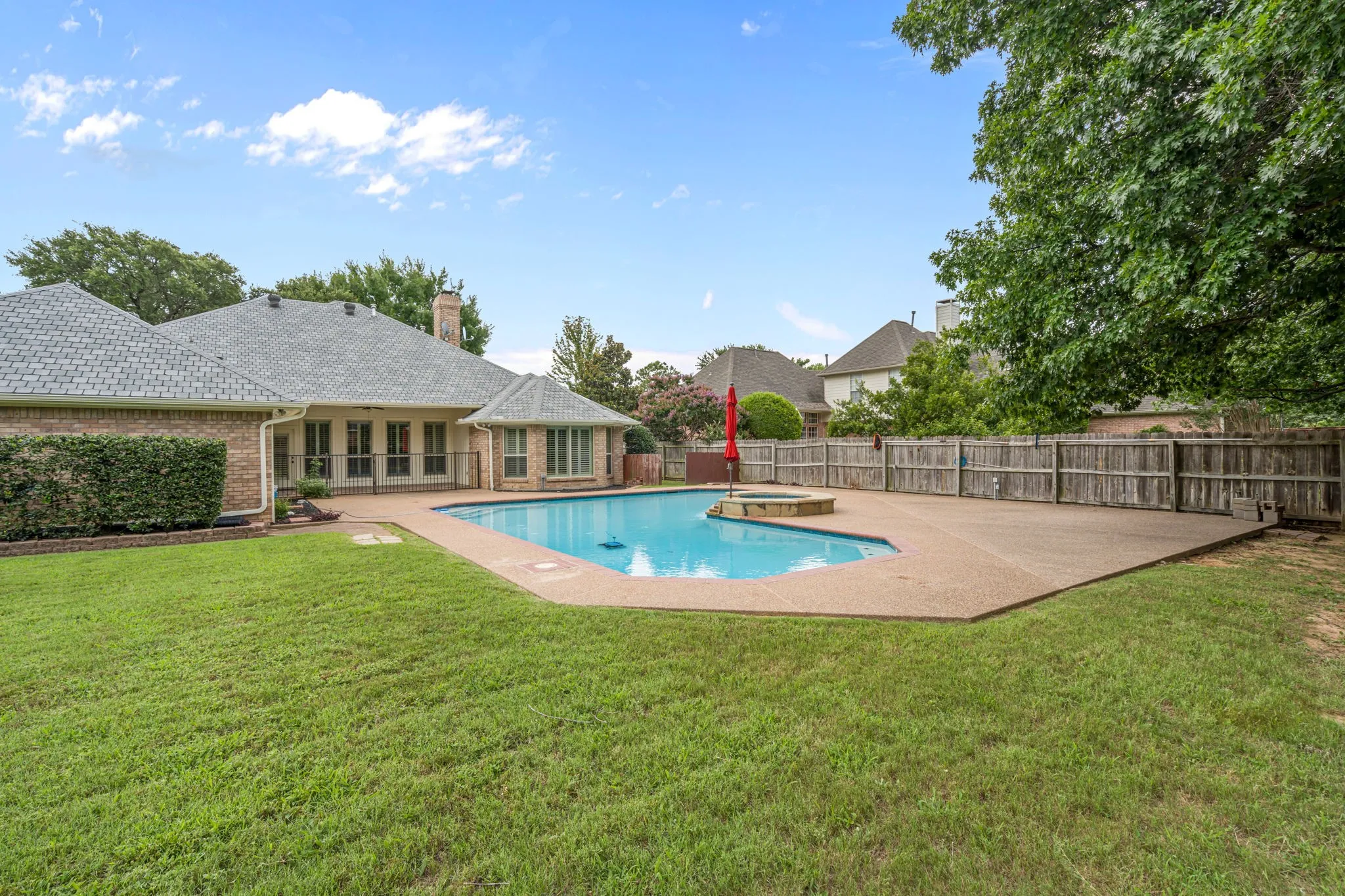 Expansive backyard featuring a swimming pool, integrated spa, and concrete deck