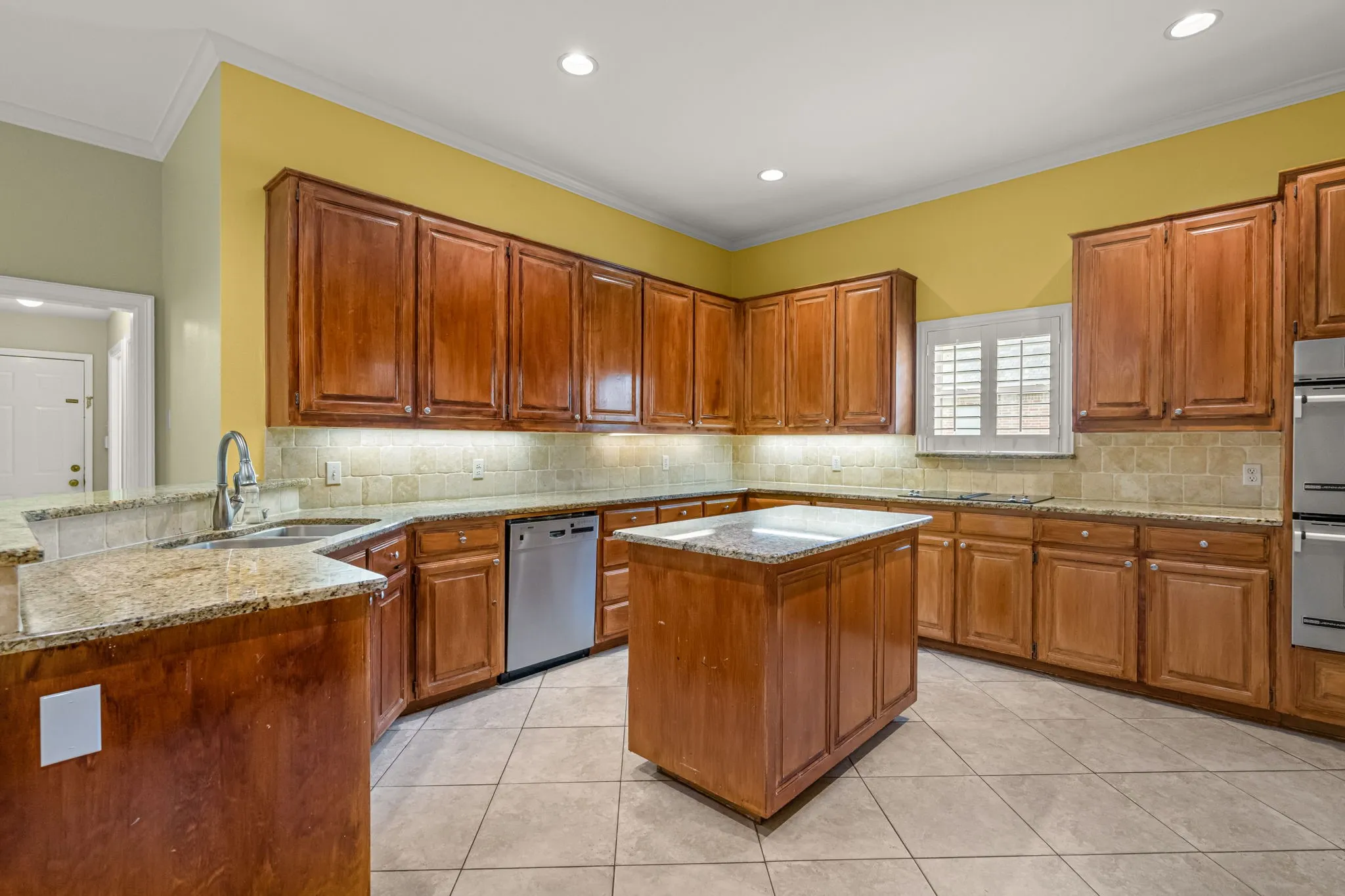 Kitchen featuring extensive wood cabinetry, stone countertops, a central island, stainless steel appliances, and recessed lighting