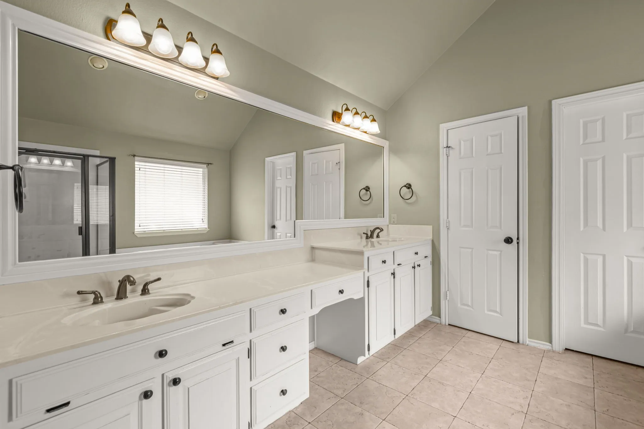 Bathroom featuring a double vanity with white cabinetry, light-toned countertops, and bronze-finish fixtures