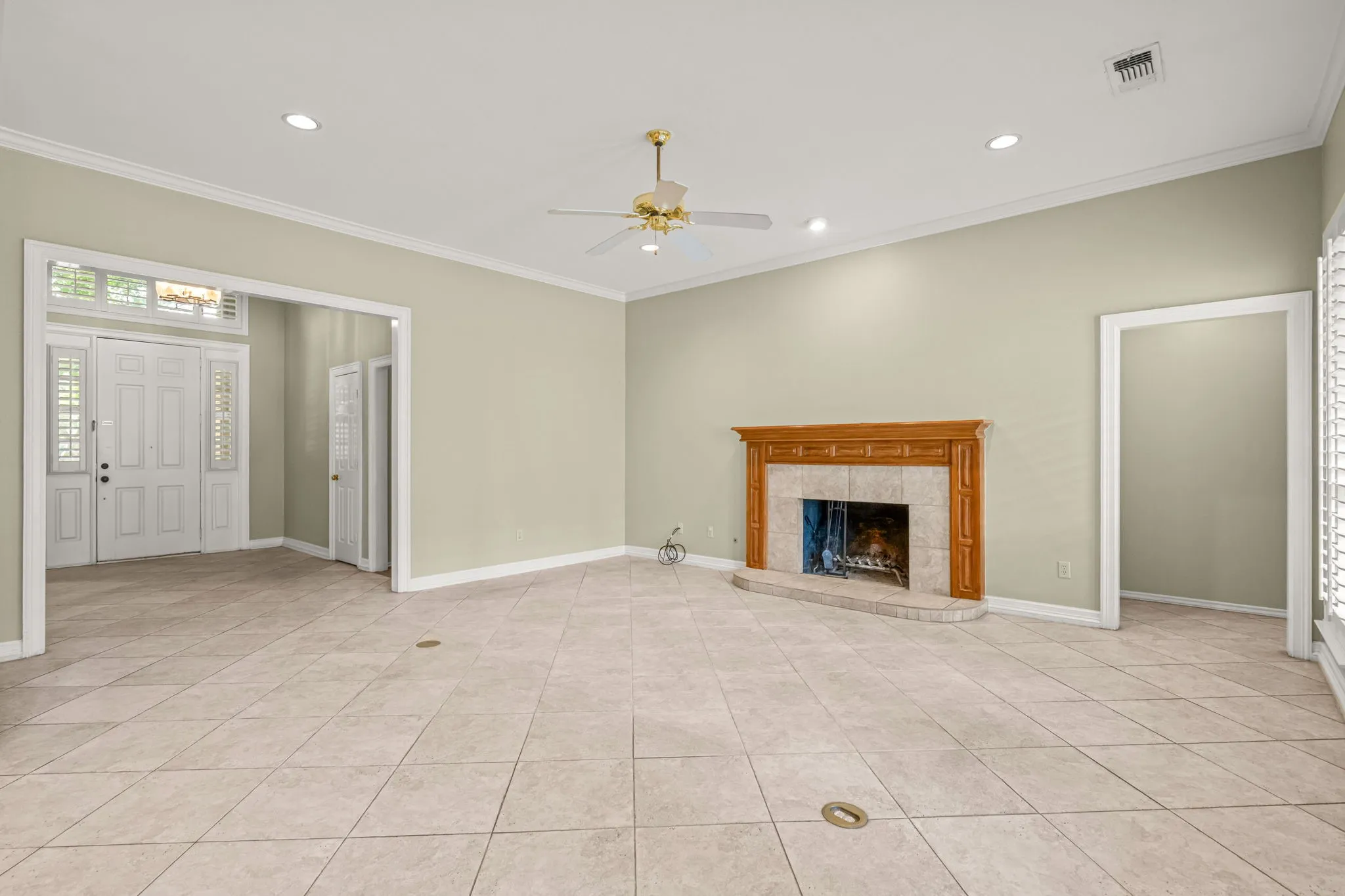 Spacious living area featuring neutral wall tones, tile flooring, a decorative wood mantel, recessed lighting, and a ceiling fan