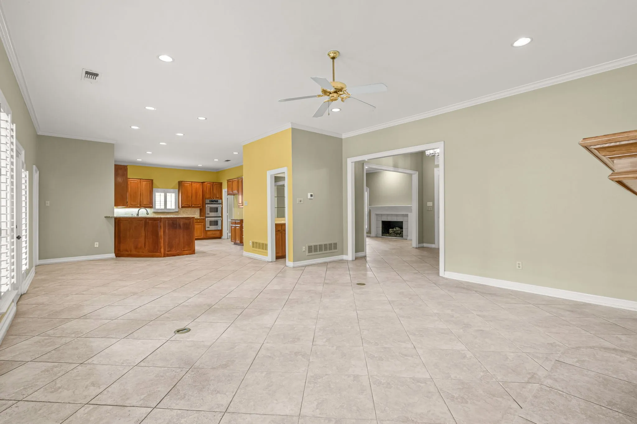 Open-concept living area featuring tile flooring, crown molding, and recessed lighting