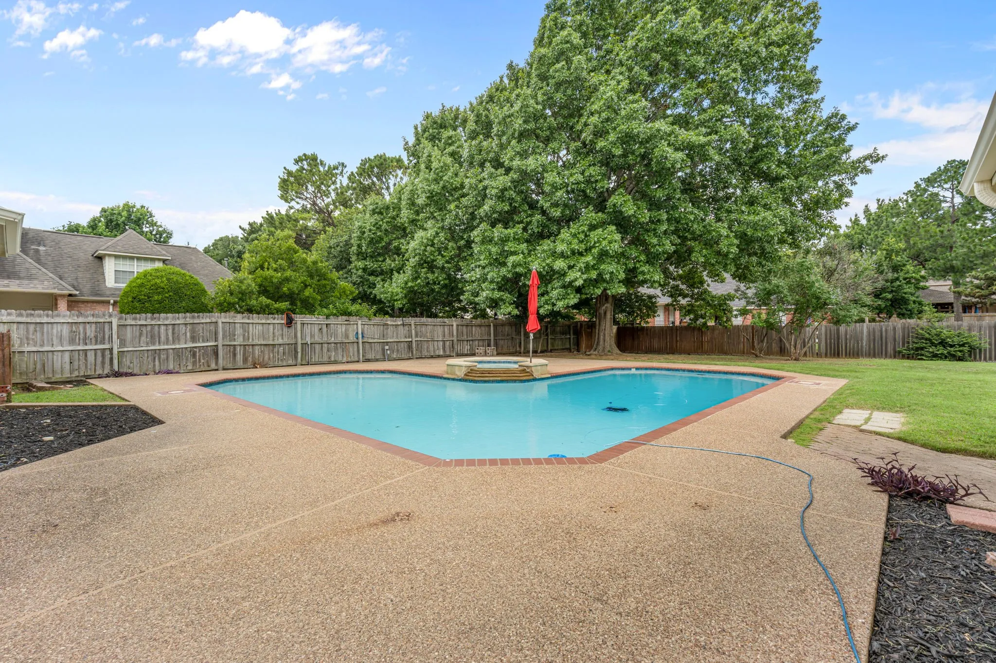 Expansive backyard featuring a custom-shaped swimming pool with an integrated spa