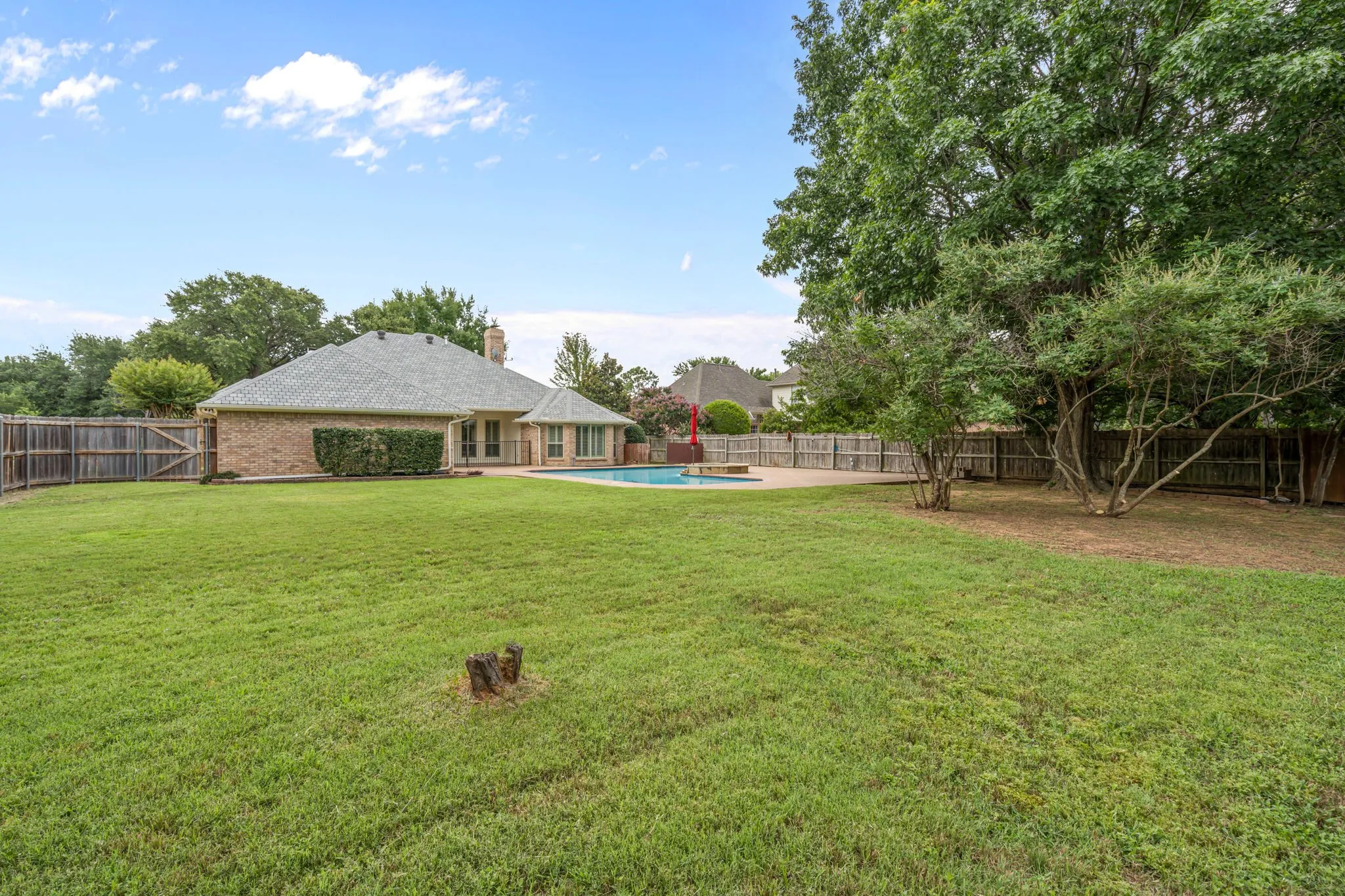 Expansive grass lawn with mature trees and a privacy fence