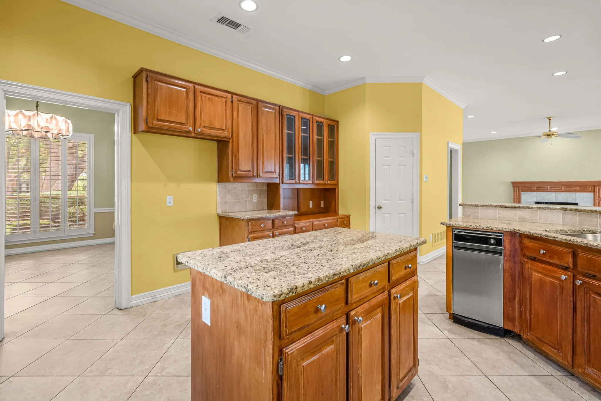 Kitchen featuring a granite-topped island, wood cabinetry, tile flooring, and recessed lighting