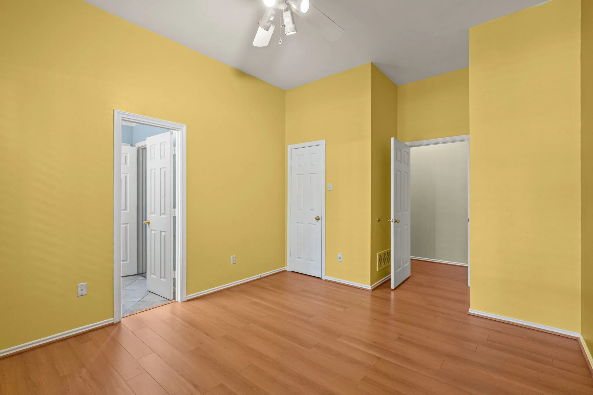 Room with wood-finish flooring, vaulted ceiling, and a ceiling fan