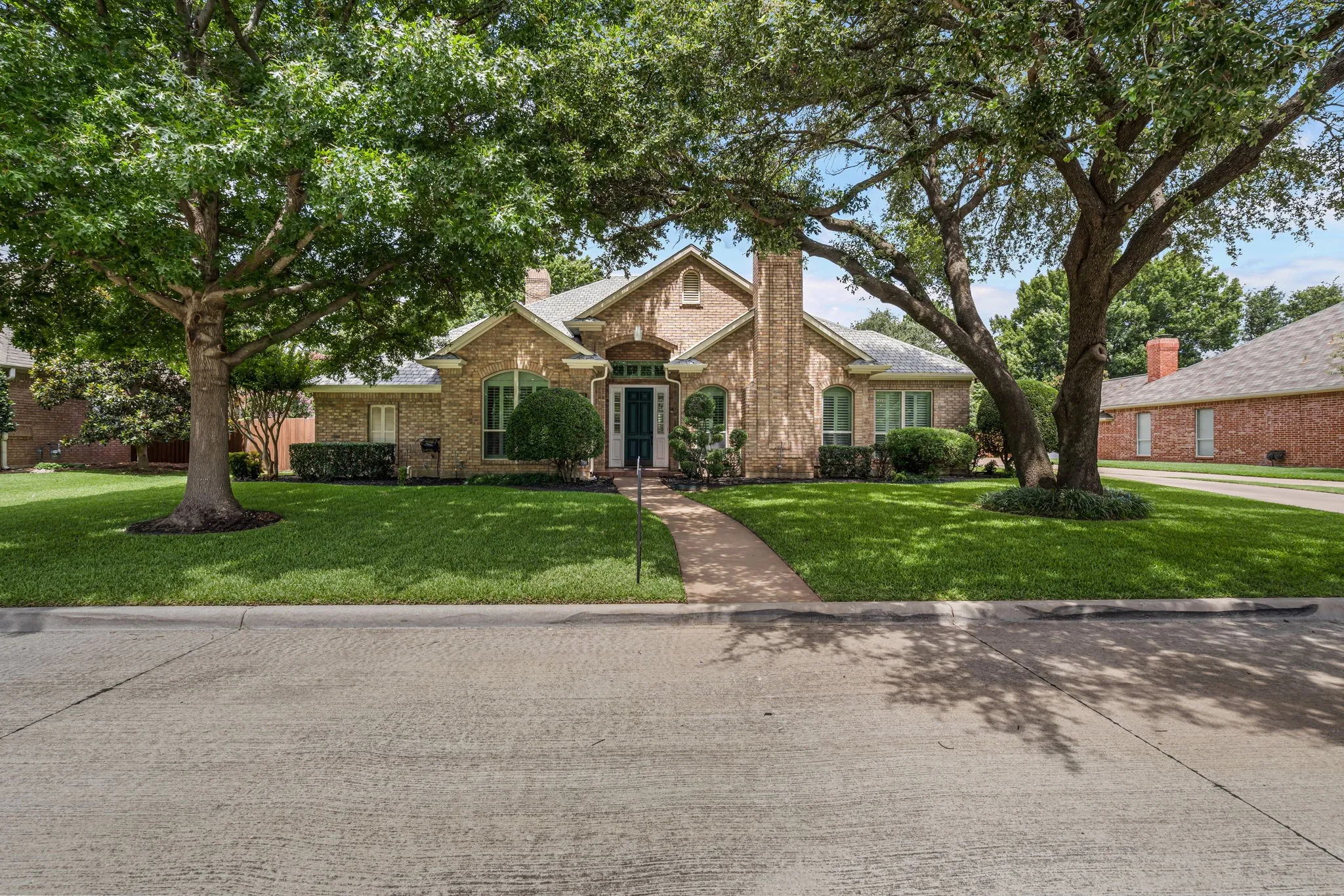 Brick exterior residential property featuring a prominent entry with an arched portico and a dark green door