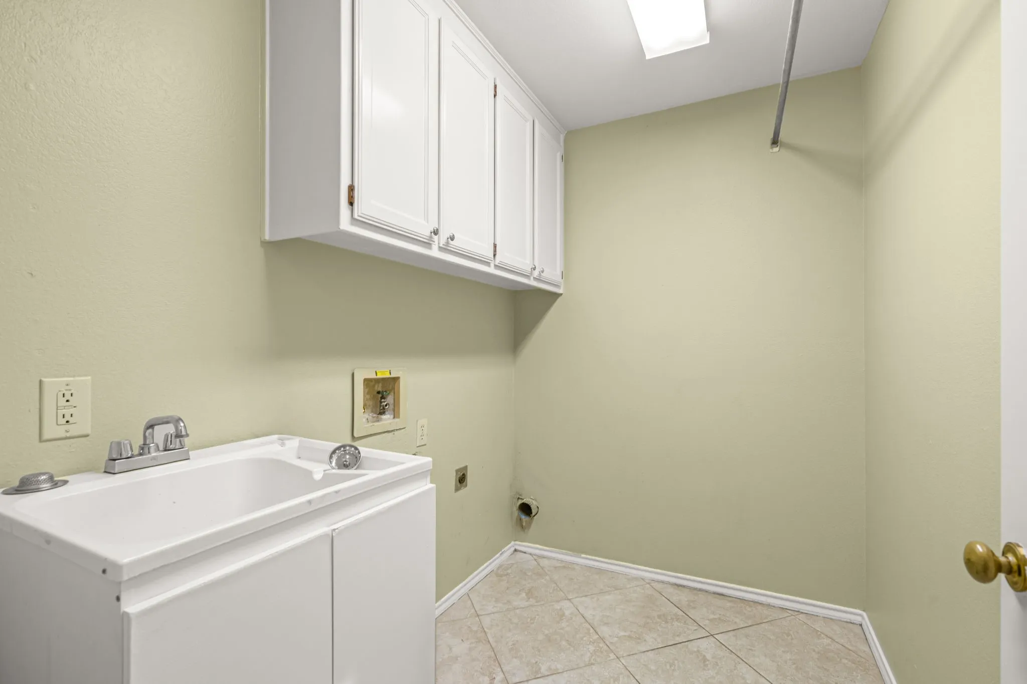 Laundry area featuring a utility sink, upper cabinetry, and tile flooring