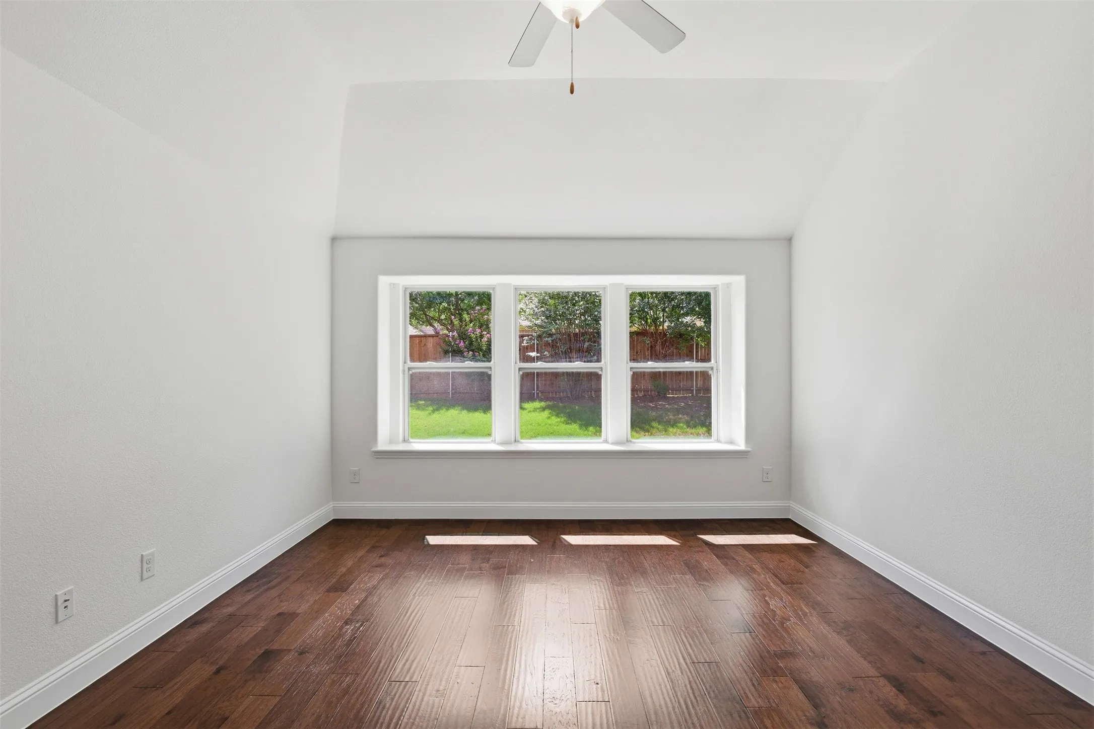 Room featuring a three-panel bay window, vaulted ceiling, and dark wood-finish flooring