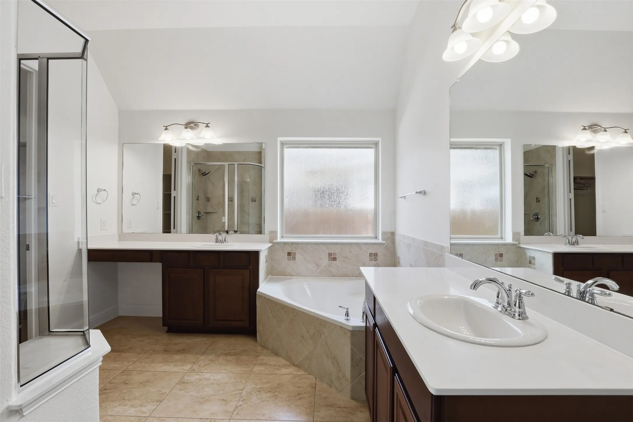 Bathroom featuring dual vanities with white countertops, wood cabinetry, and chrome fixtures