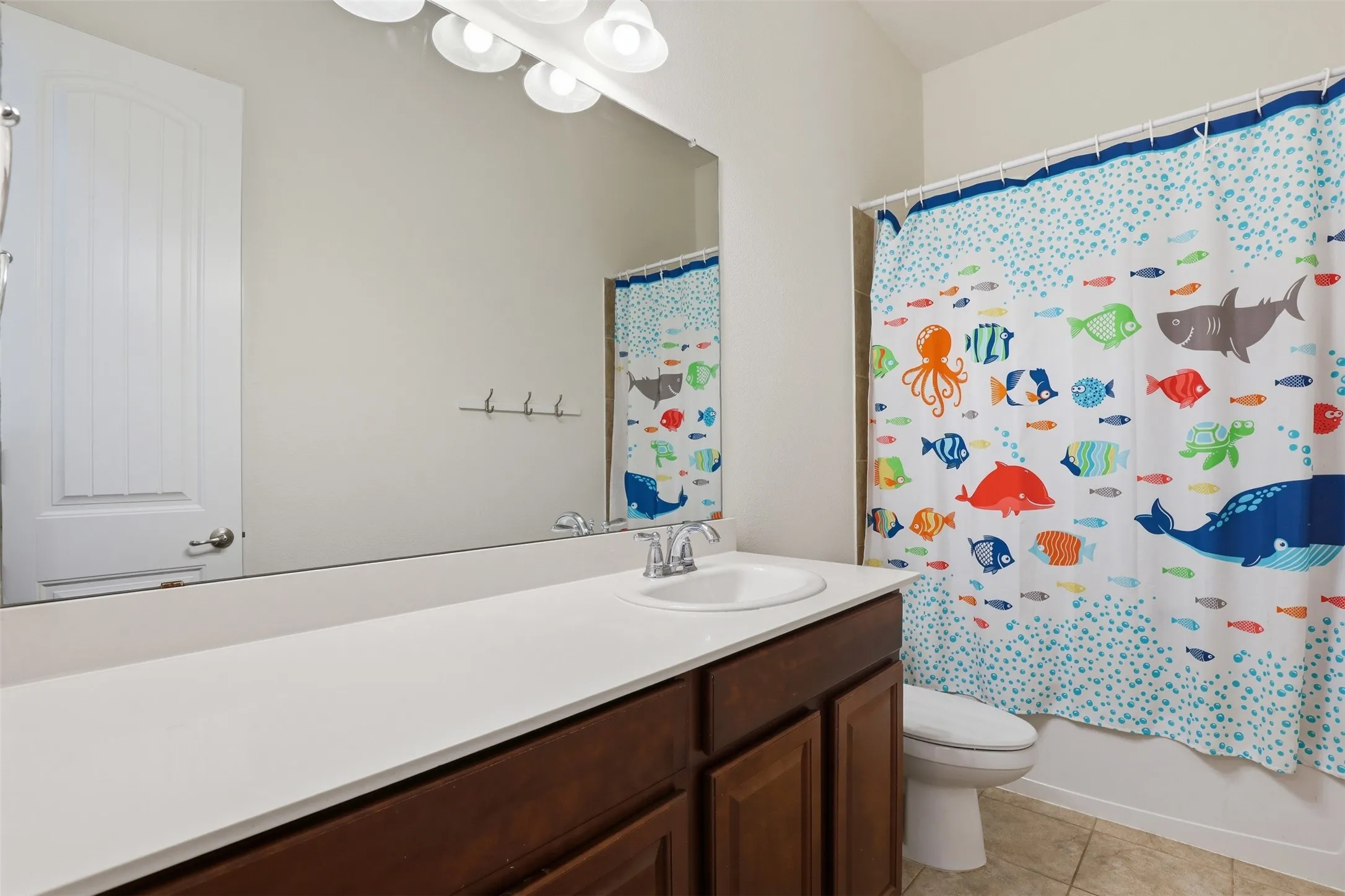 Bathroom featuring an expansive vanity with an integrated sink, wood-finish cabinetry, and a full-width mirror
