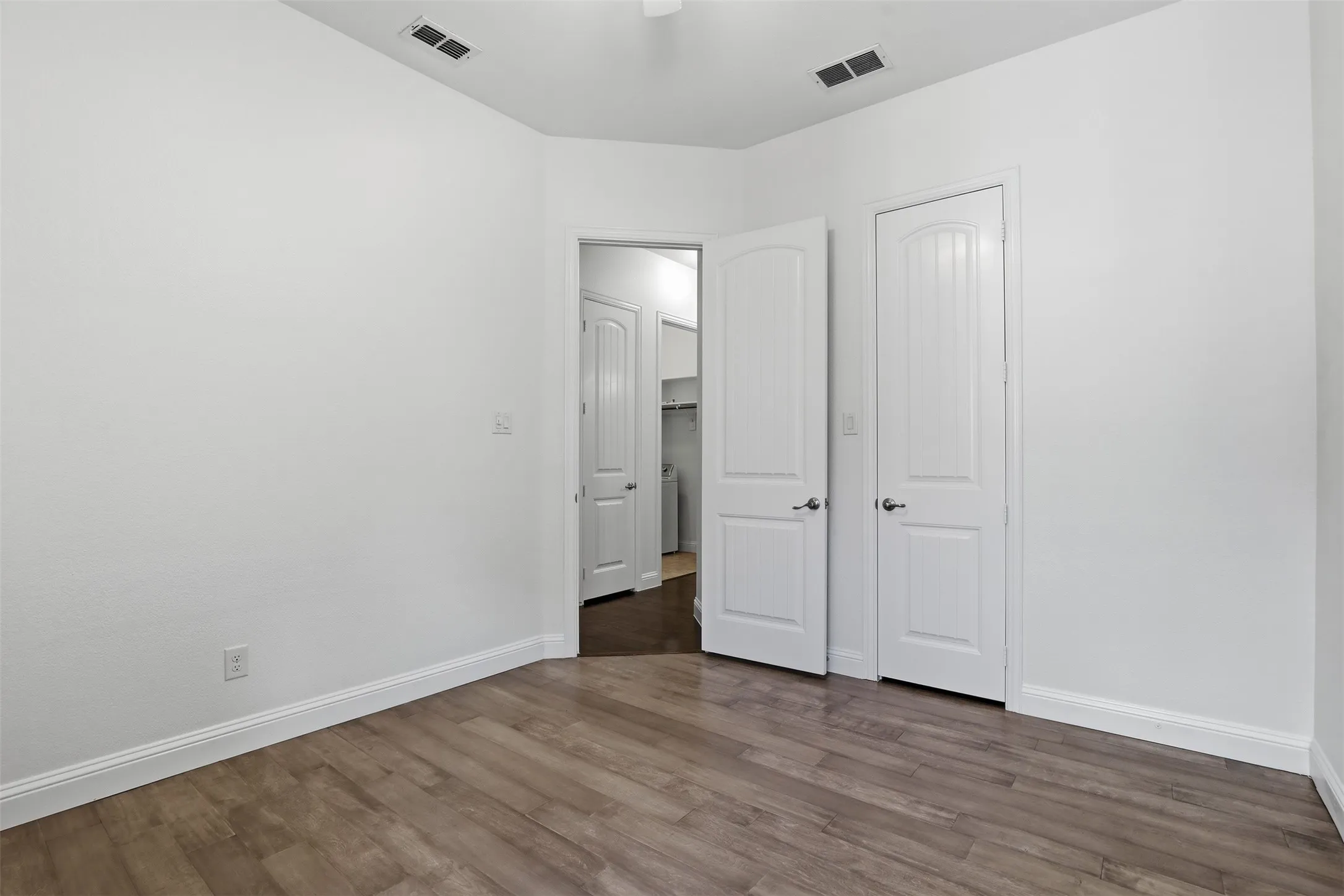 Neutral white walls with crisp white baseboards and wood-finish plank flooring