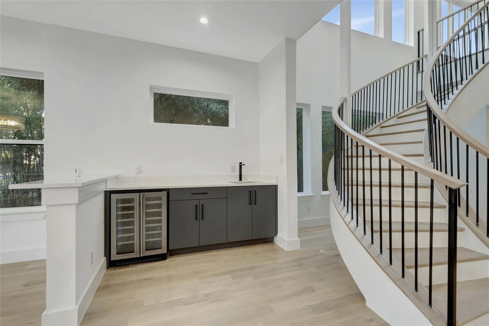 Curved staircase with black metal balusters and wood-finish handrail
