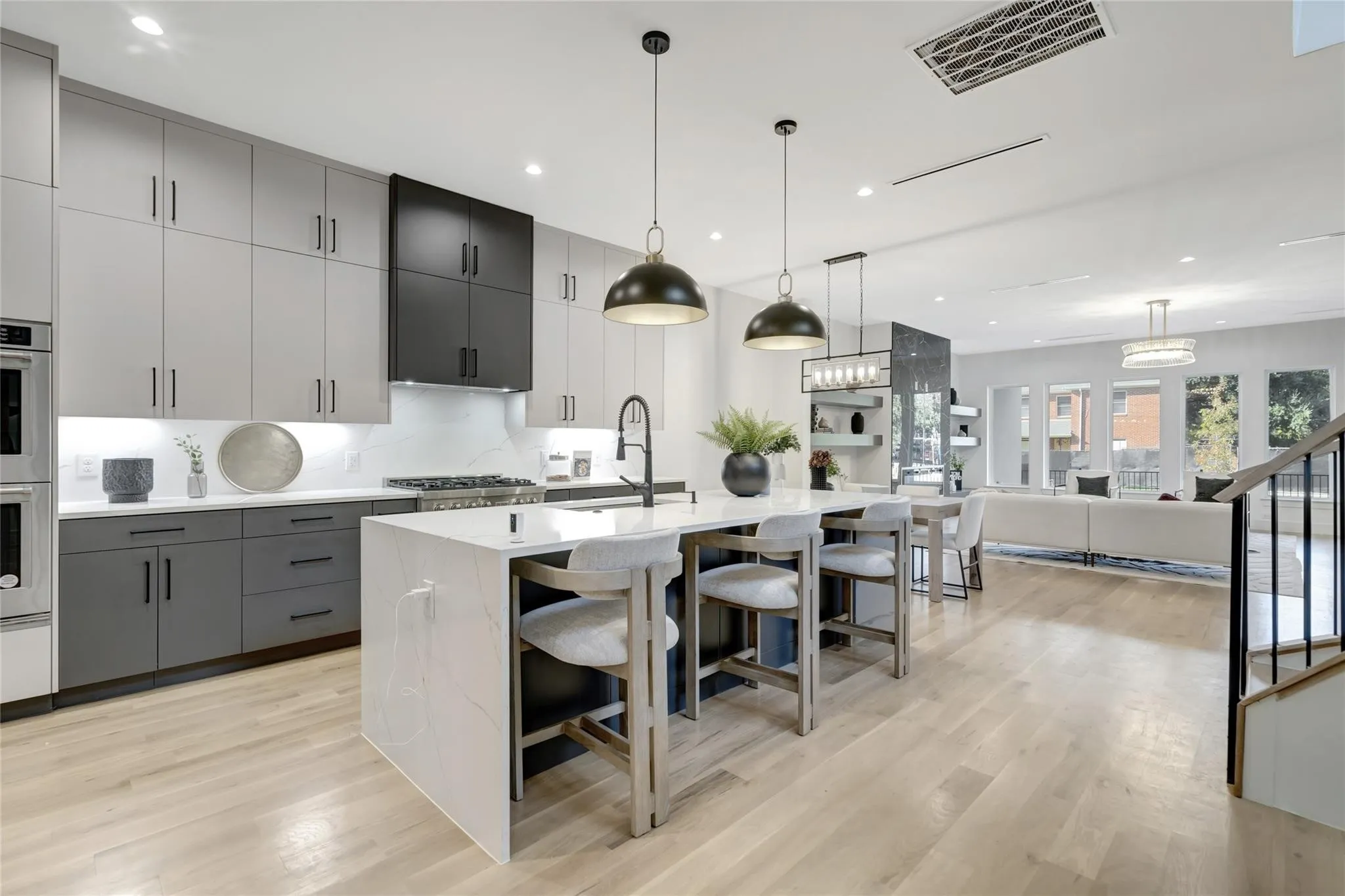 Gourmet kitchen with two-tone cabinetry, a waterfall island, stainless steel appliances, and wood-finish flooring