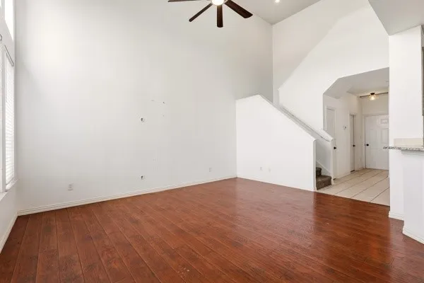Spacious living area featuring wood-finish flooring, high ceilings, and a ceiling fan