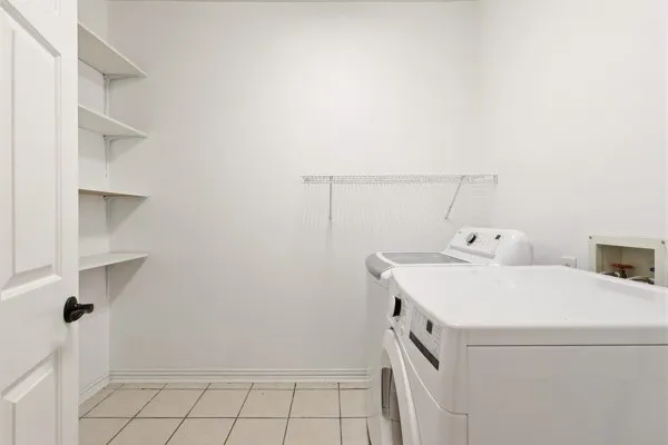 Dedicated utility space featuring tile flooring, white walls, and built-in shelving