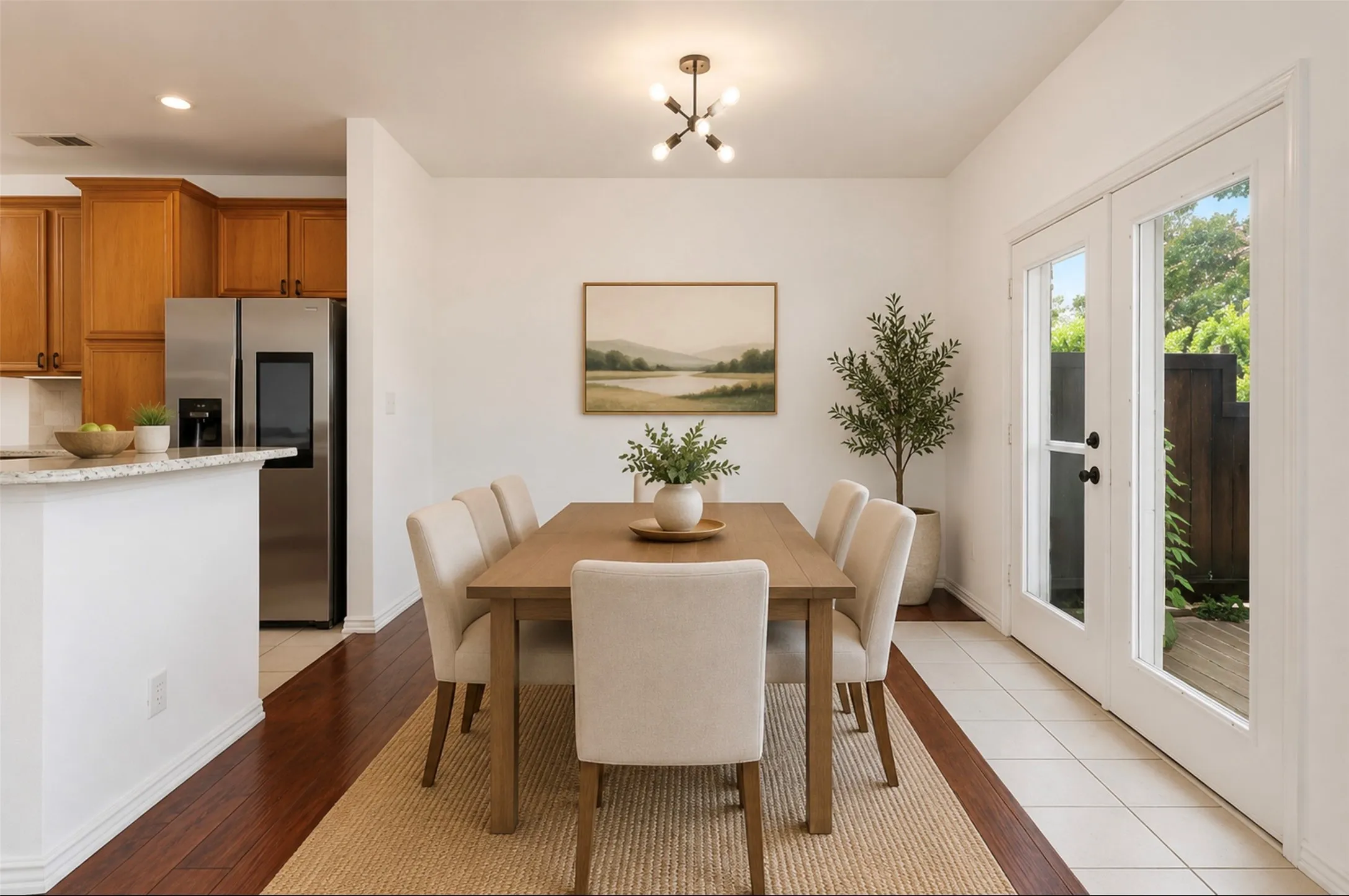 Dining area featuring wood-finish flooring, a contemporary chandelier, and French doors