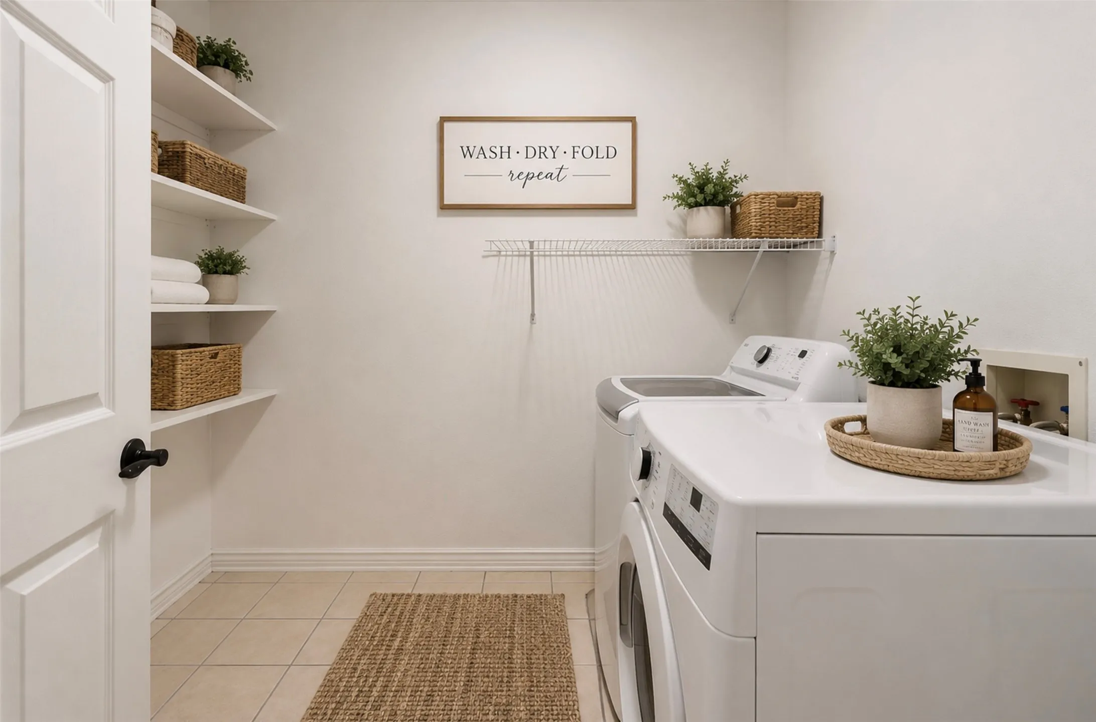 Dedicated laundry space featuring tile flooring, built-in shelving, a white paneled door with black hardware, and a wire rack