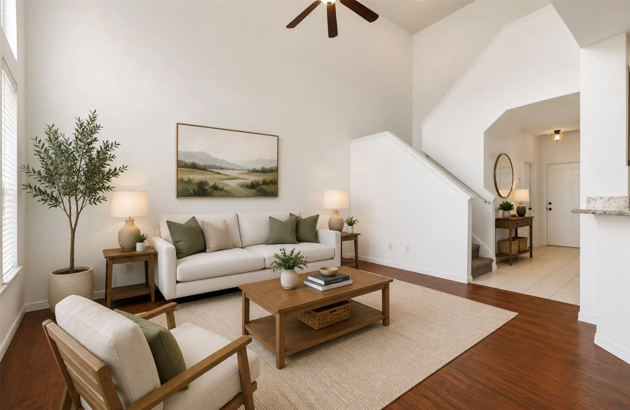 Living area featuring high ceilings, wood-finish flooring, and a ceiling fan