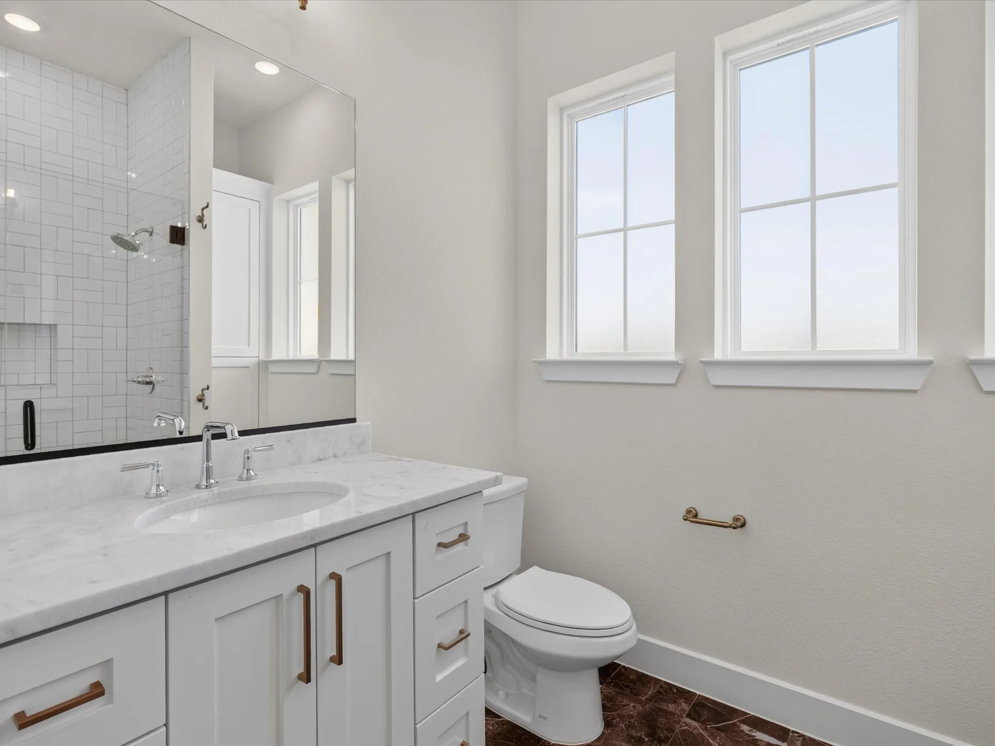 White vanity with bronze-finish hardware, polished chrome fixtures, and a white countertop