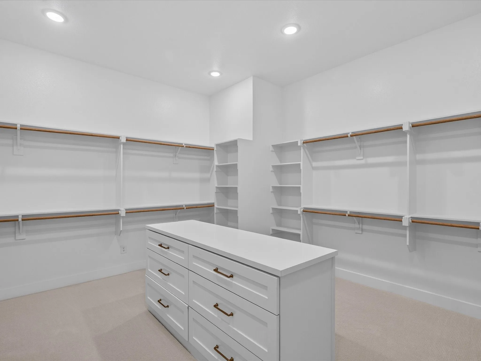 Custom closet organization system featuring a central island with drawers, extensive shelving, ample hanging rods, and recessed lighting