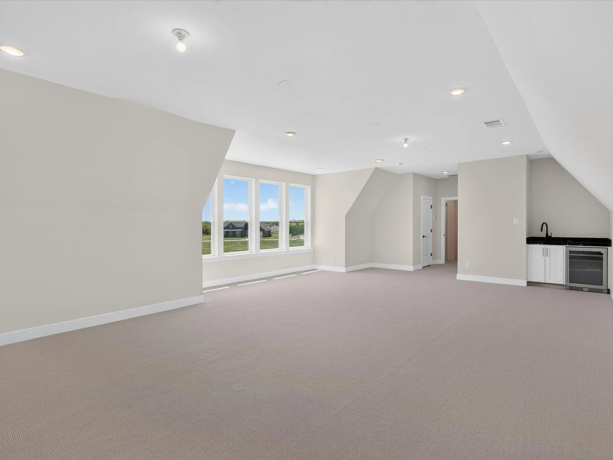 Expansive open room featuring a built-in wet bar with a dark countertop, white cabinetry, and an under-counter appliance