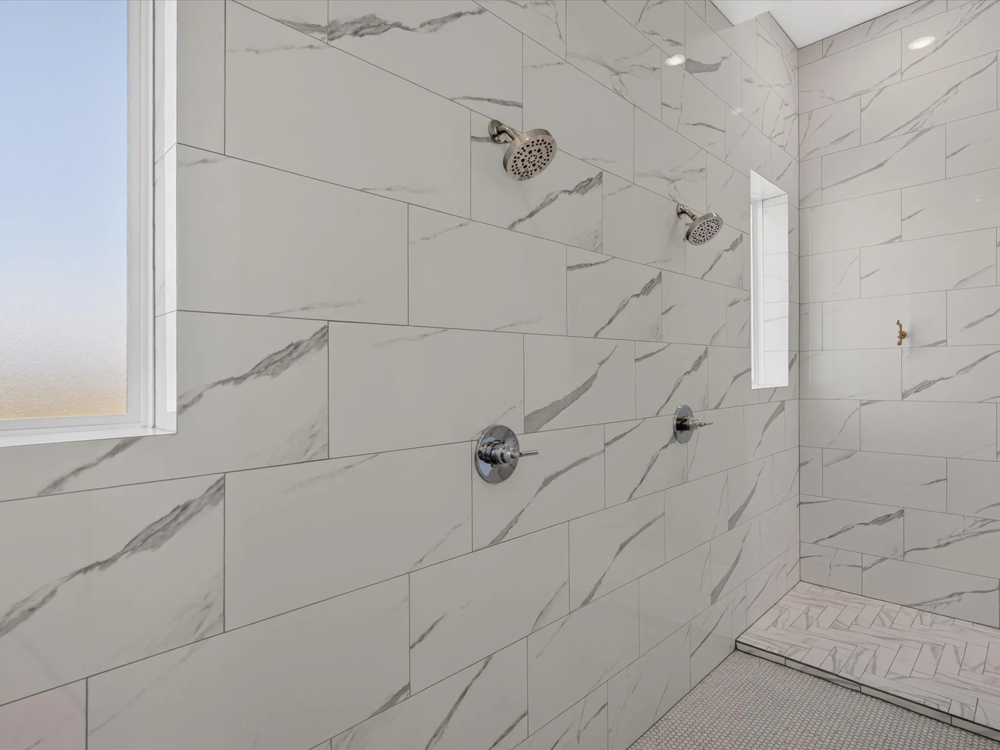 Spacious shower enclosure with floor-to-ceiling tile, dual showerheads, dual control valves, and two integrated windows