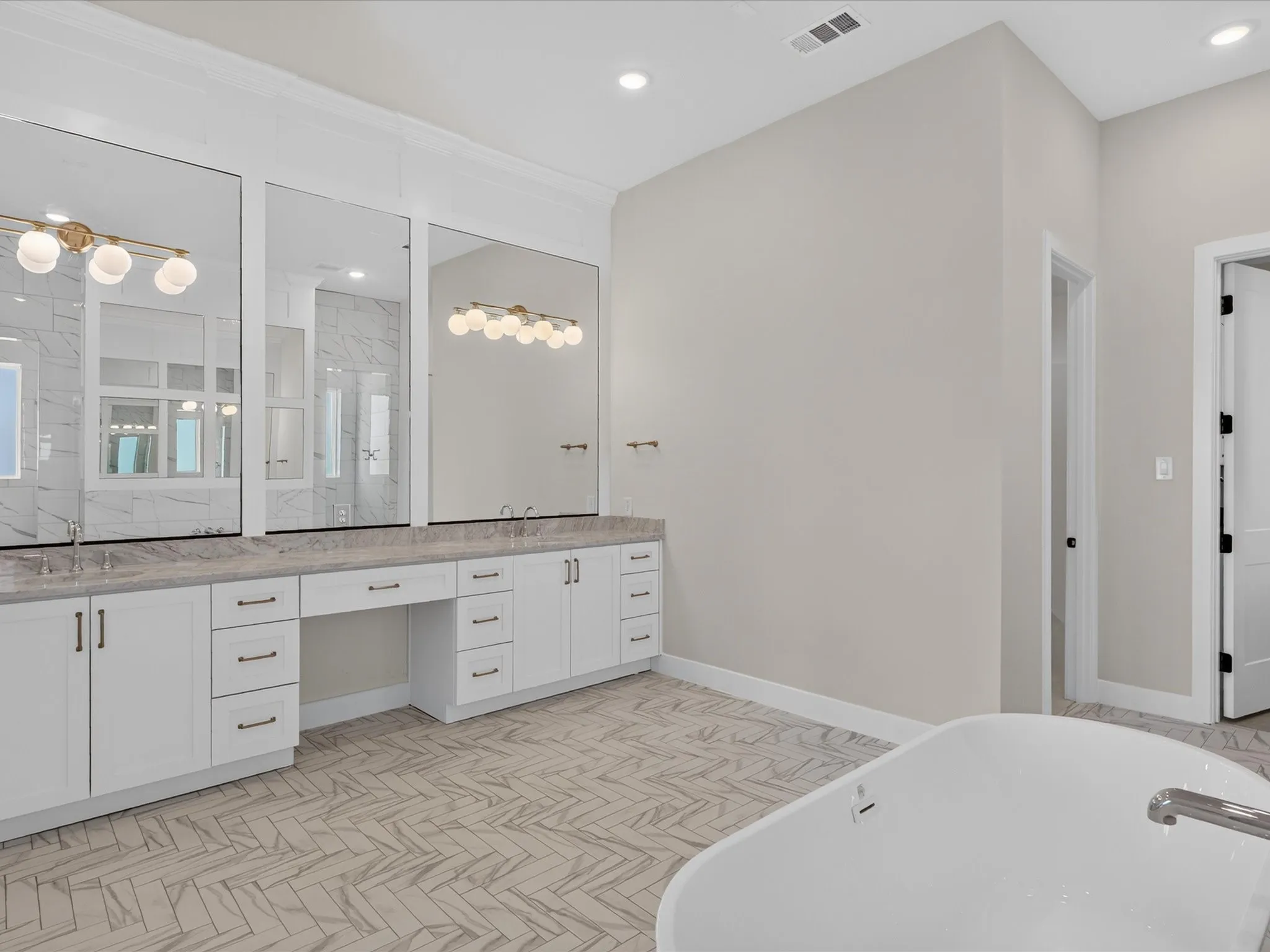 Dual vanities with white cabinetry, integrated sinks, and polished countertops