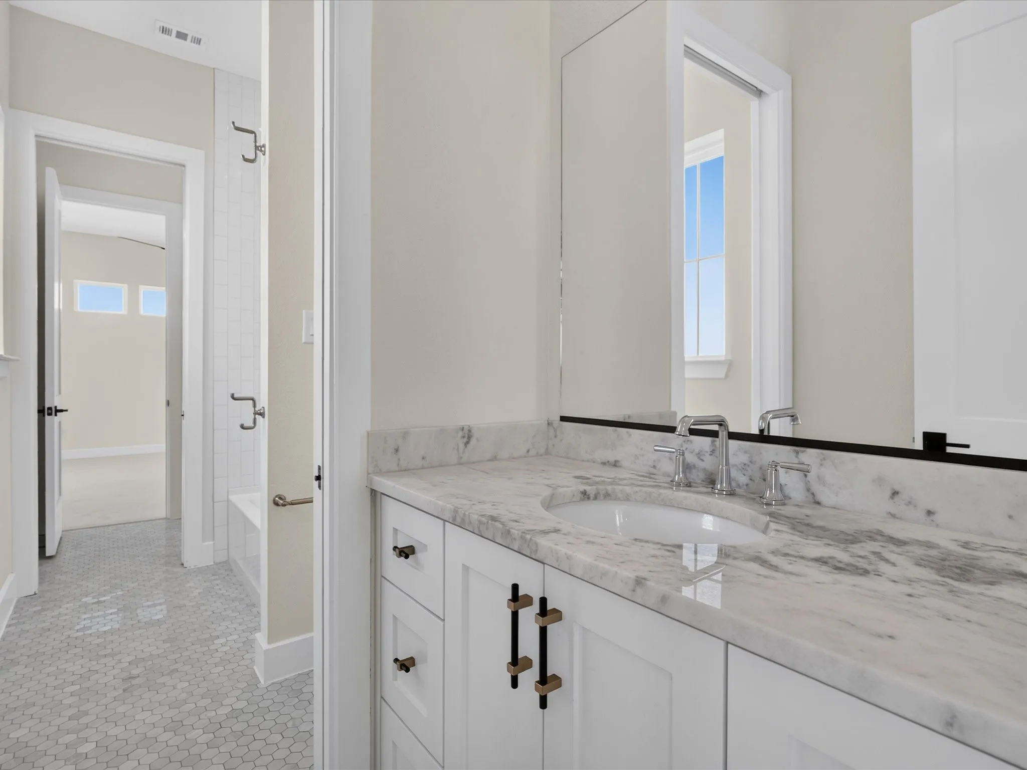 White vanity with panel-front cabinetry, an undermount sink, and a stone countertop