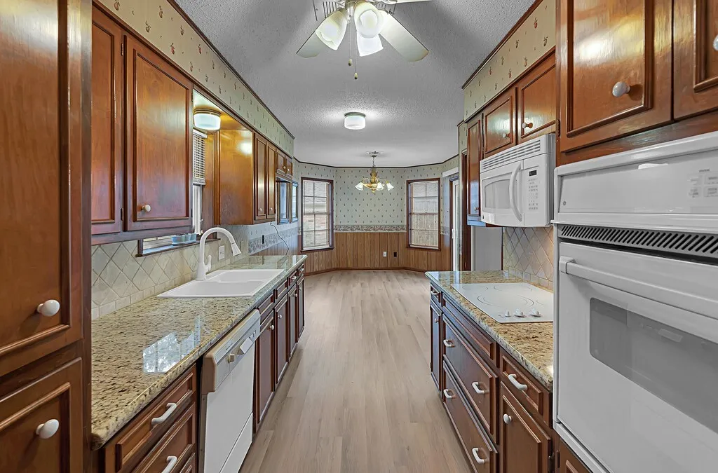 Galley kitchen featuring wood cabinetry & granite-finish countertops,