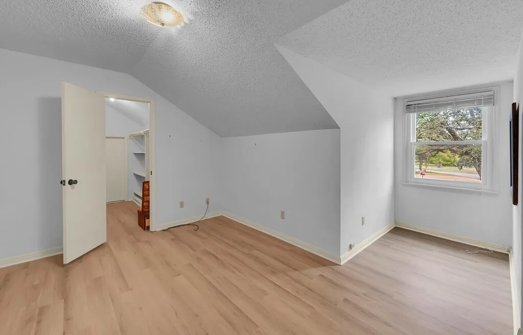 Room featuring Luxury Viynl Flooring Nook Windo with Blinds, and an Open Doorway revealing a Closet with Shelving & Walk-in Door to Attic