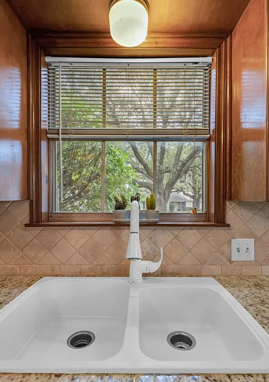Double basin sink with a modern white faucet, set against granite countertops and a diamond-patterned tile backsplash