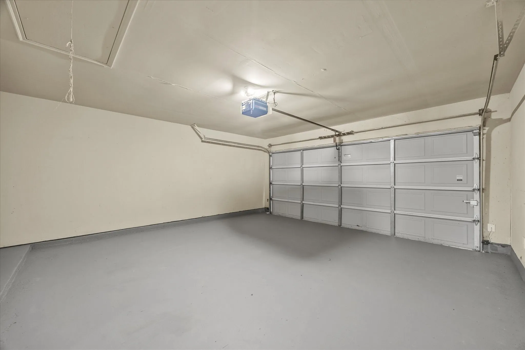 Spacious garage with a light gray painted floor and cream-colored walls