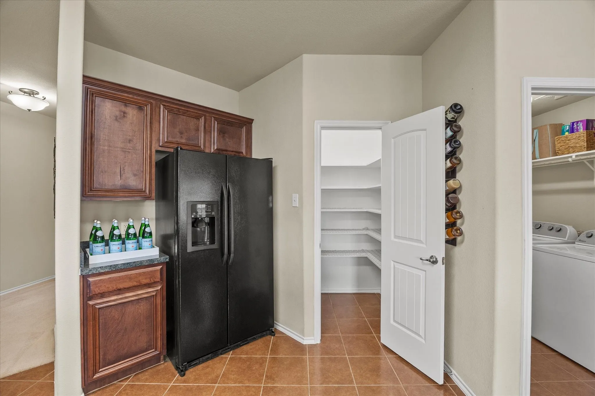 Kitchen area featuring tile flooring and a built-in wood-finish cabinet with a dark countertop