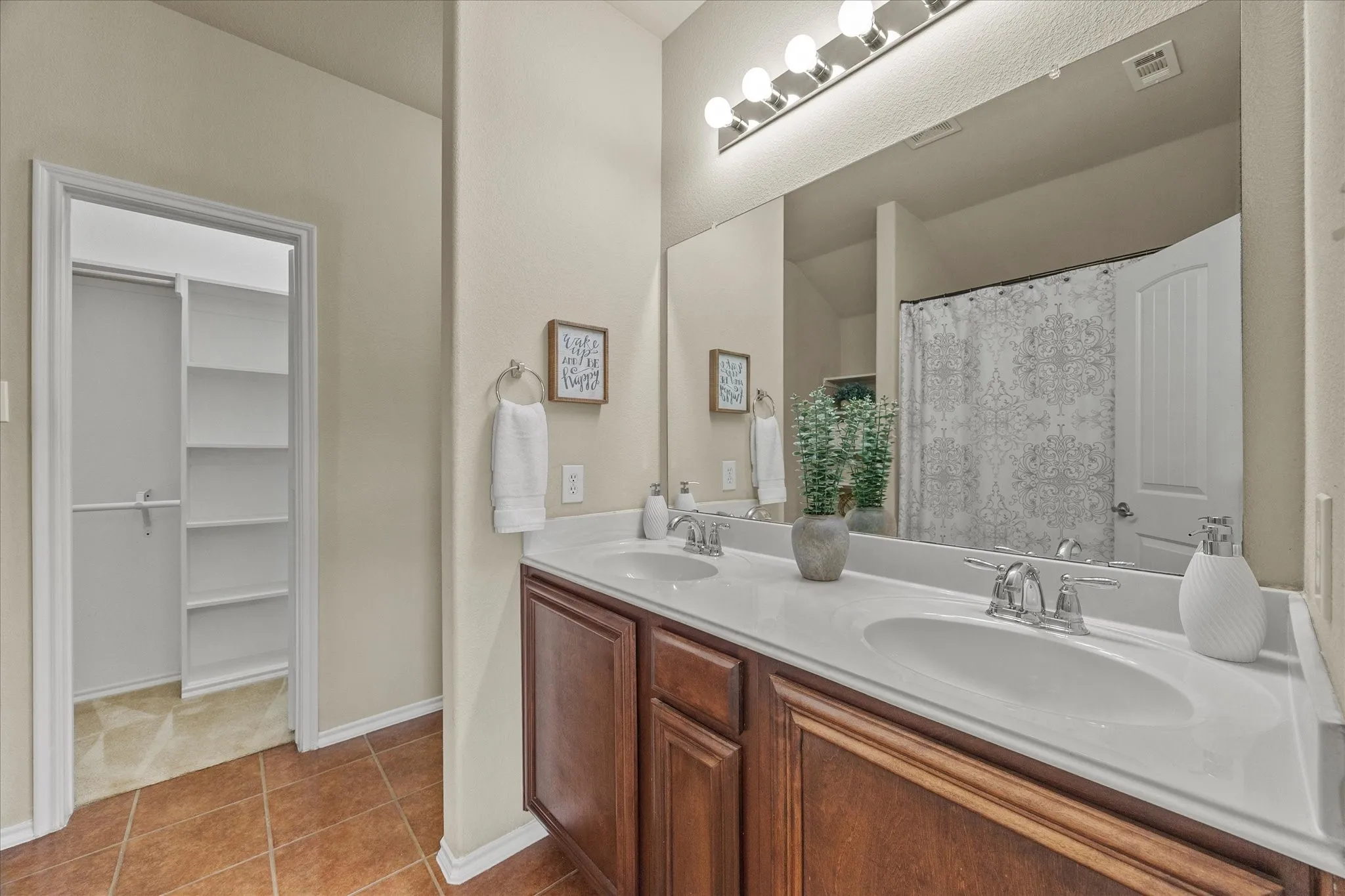 Bathroom featuring a dual vanity with integrated sinks, chrome fixtures, and a large wall-mounted mirror