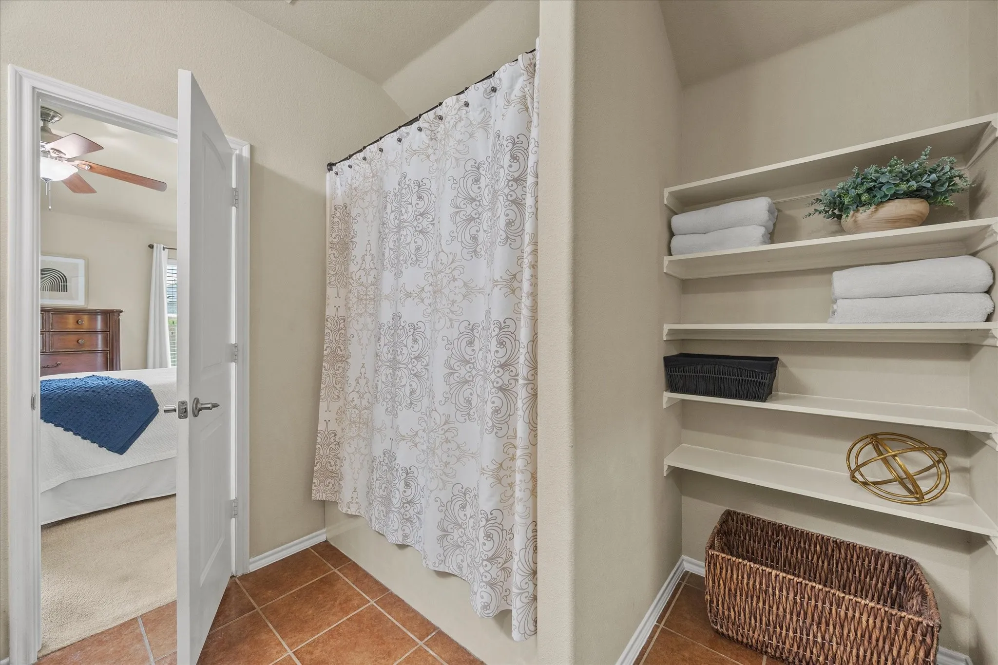 Shower area featuring terracotta-style tile flooring and a decorative shower curtain