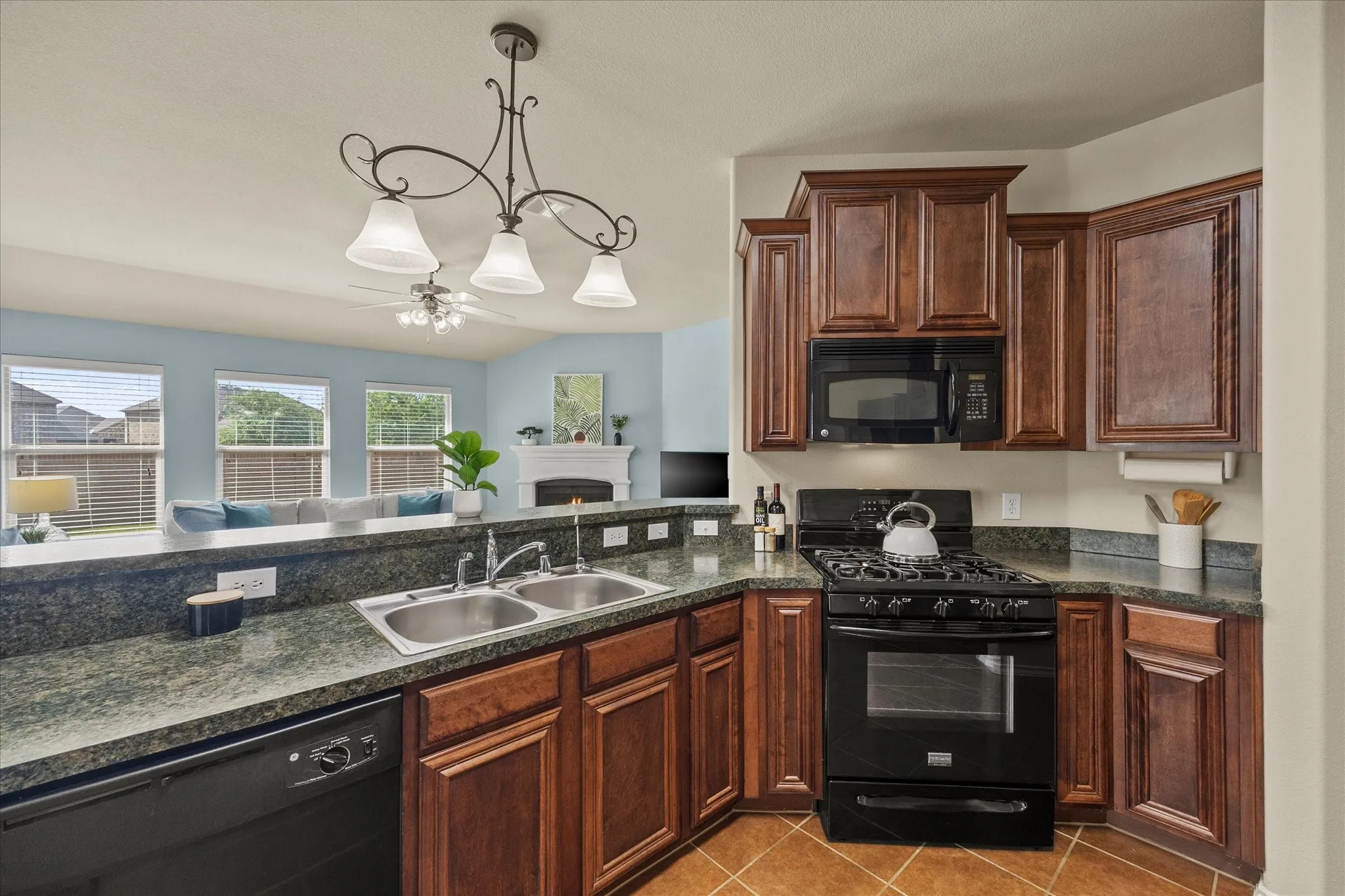Kitchen featuring dark wood cabinetry, a built-in microwave, and a black gas range
