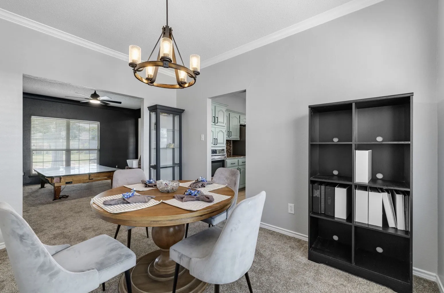 Formal dining area featuring a wood-finish chandelier, crown molding, and neutral wall tones