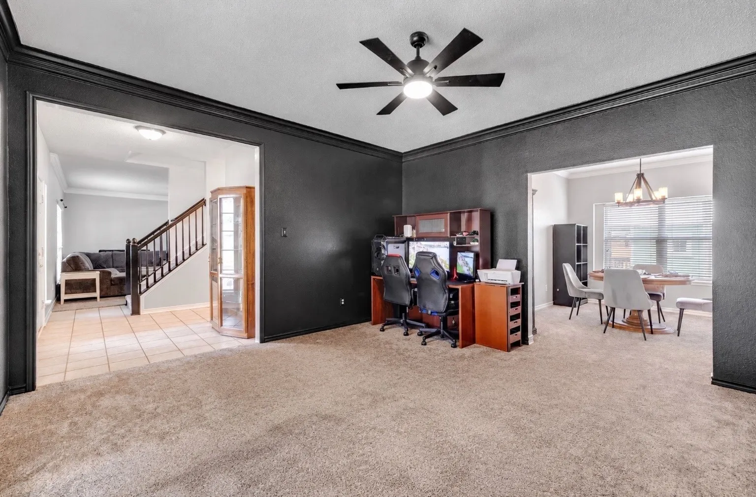 Carpeted living space featuring dark accent walls and a ceiling fan with integrated lighting