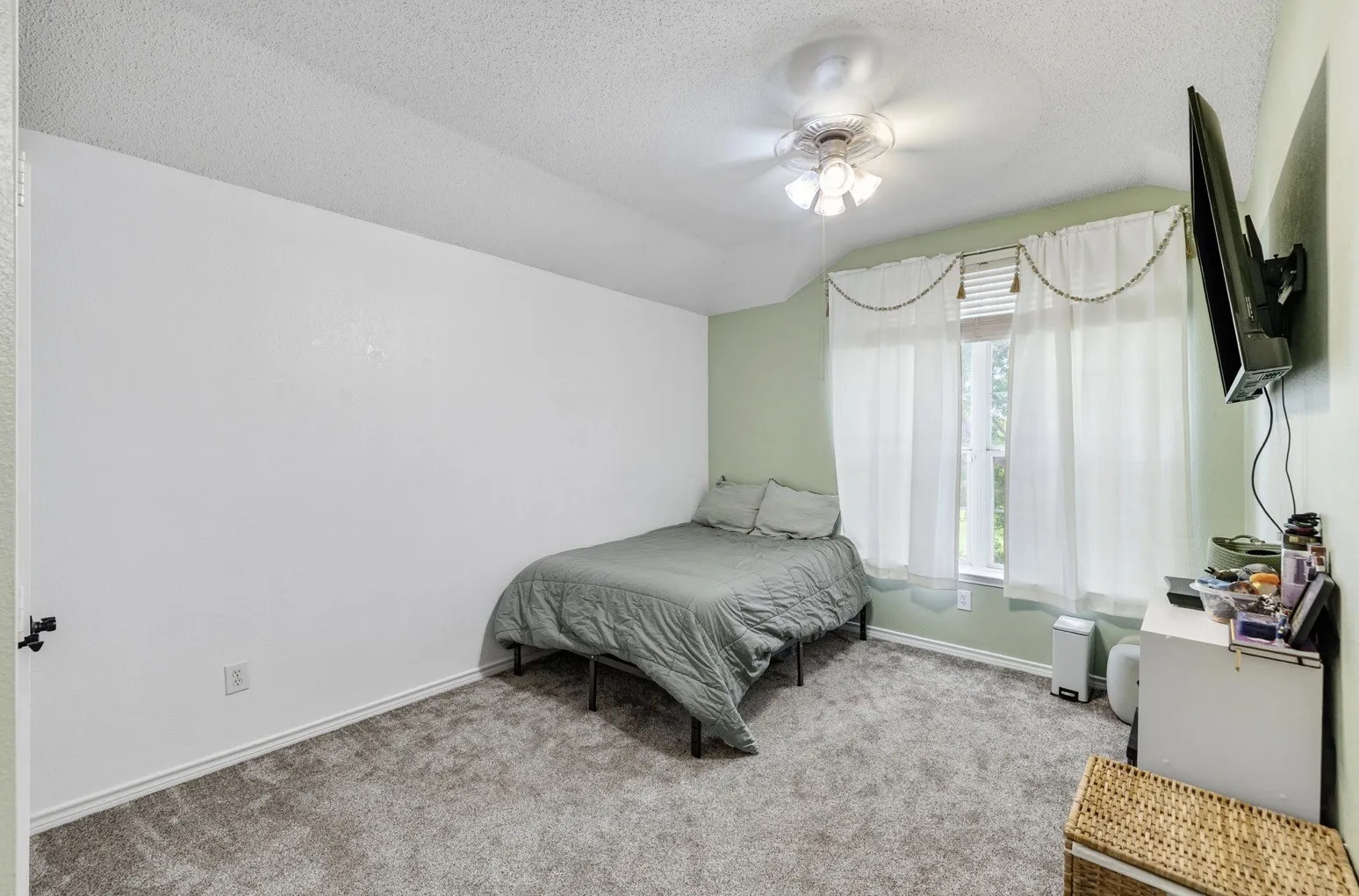 Carpeted room featuring a window with blinds and sheer curtains, a ceiling fan with integrated lighting, and white baseboards