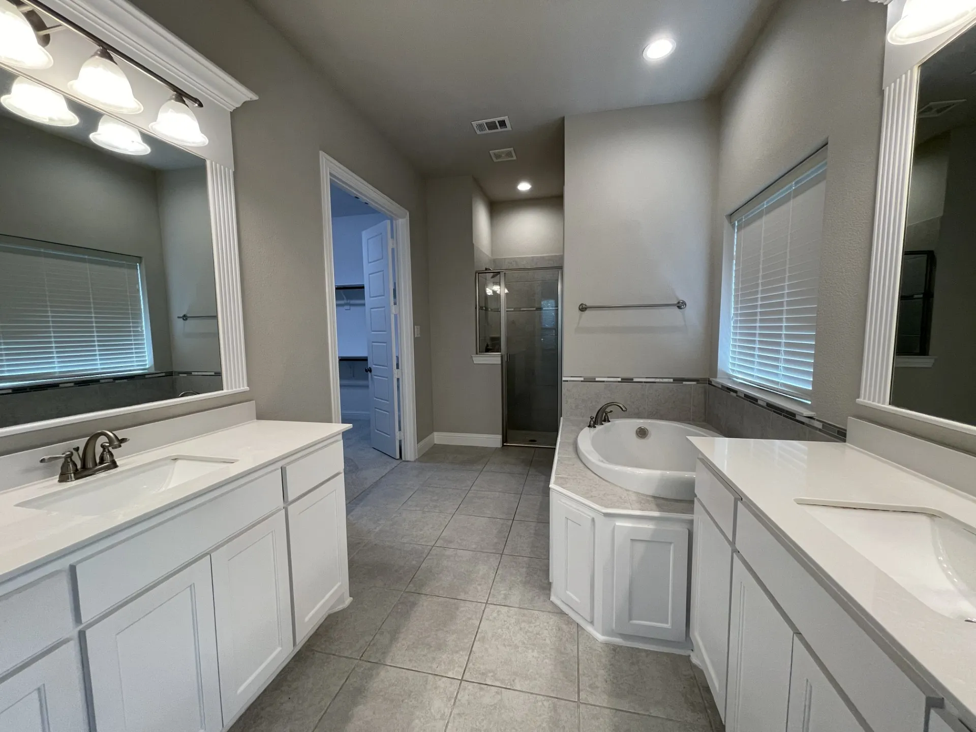 Spacious bathroom featuring dual vanities with white cabinetry and light-toned countertops