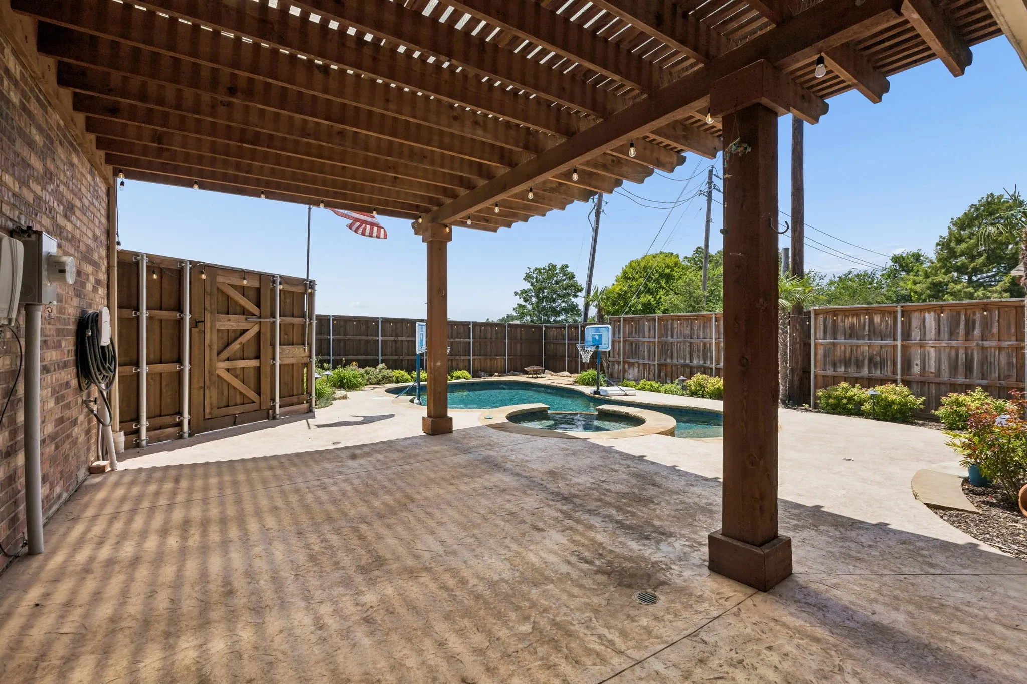 Expansive outdoor patio with a wooden pergola and string lighting