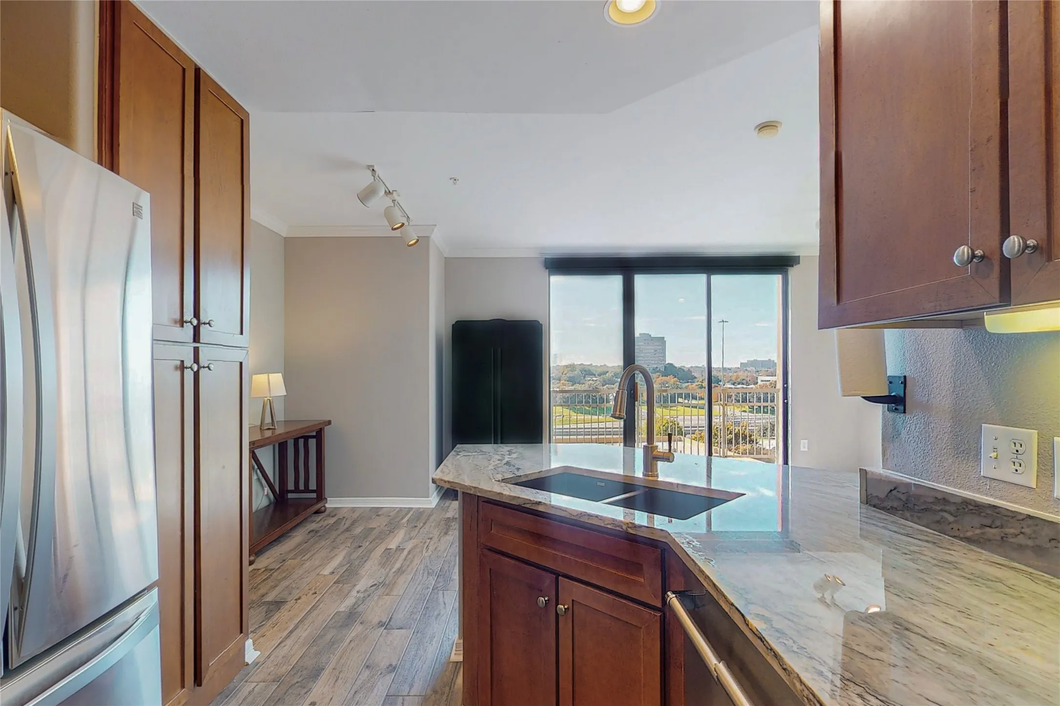 Kitchen featuring sink, ornamental molding, stainless steel appliances, light stone countertops, and light wood-type flooring