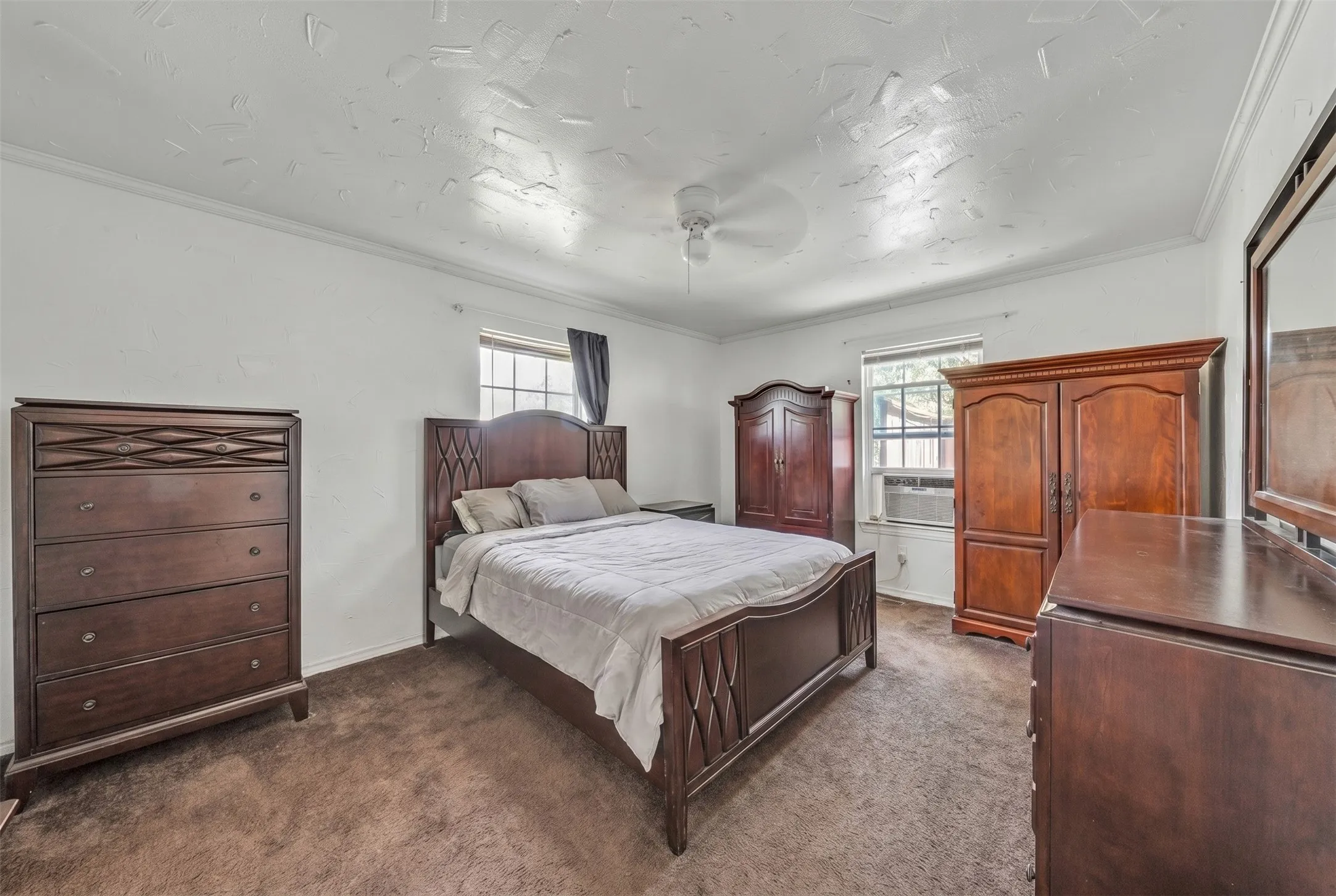 Carpeted room with white walls, a ceiling fan, and crown molding