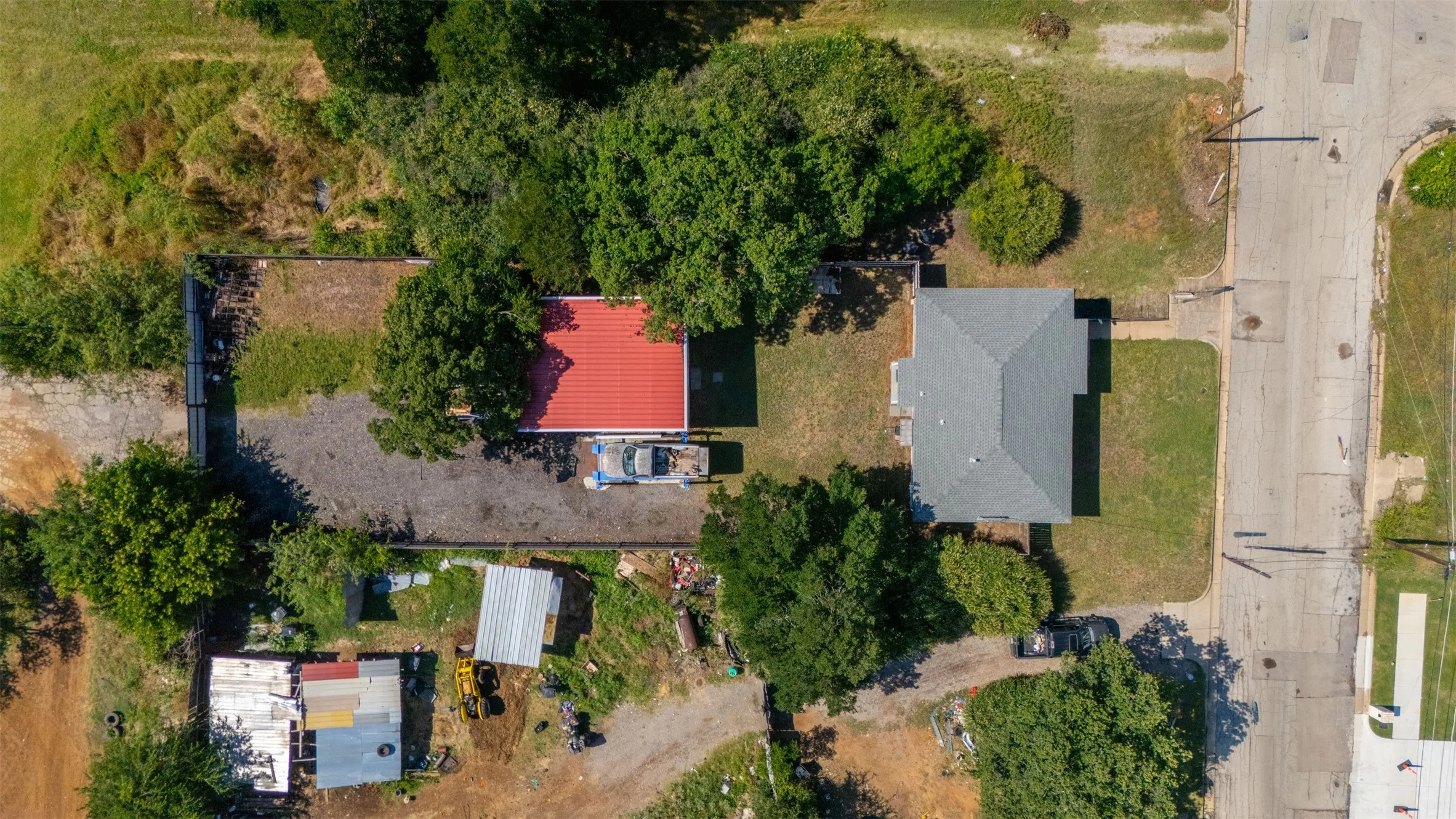 Main residence featuring a gray shingled roof, a front lawn, and mature trees