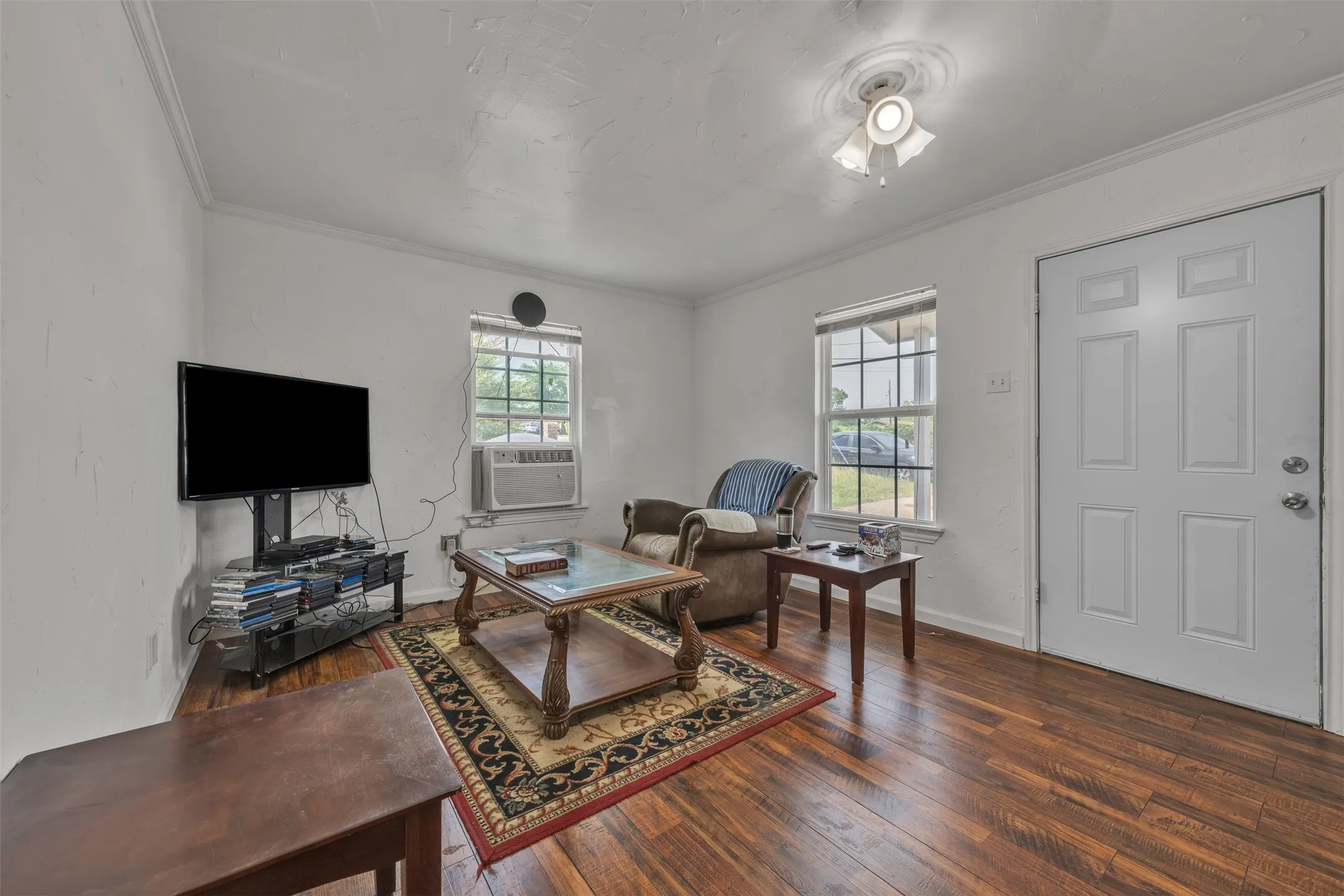 Living area featuring wood-finish flooring, white walls, and crown molding