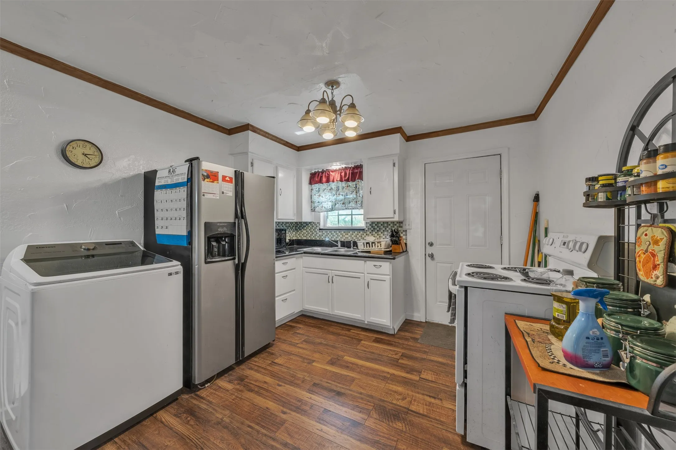 Kitchen featuring wood-finish flooring, white cabinetry, a dark countertop, and a decorative tile backsplash