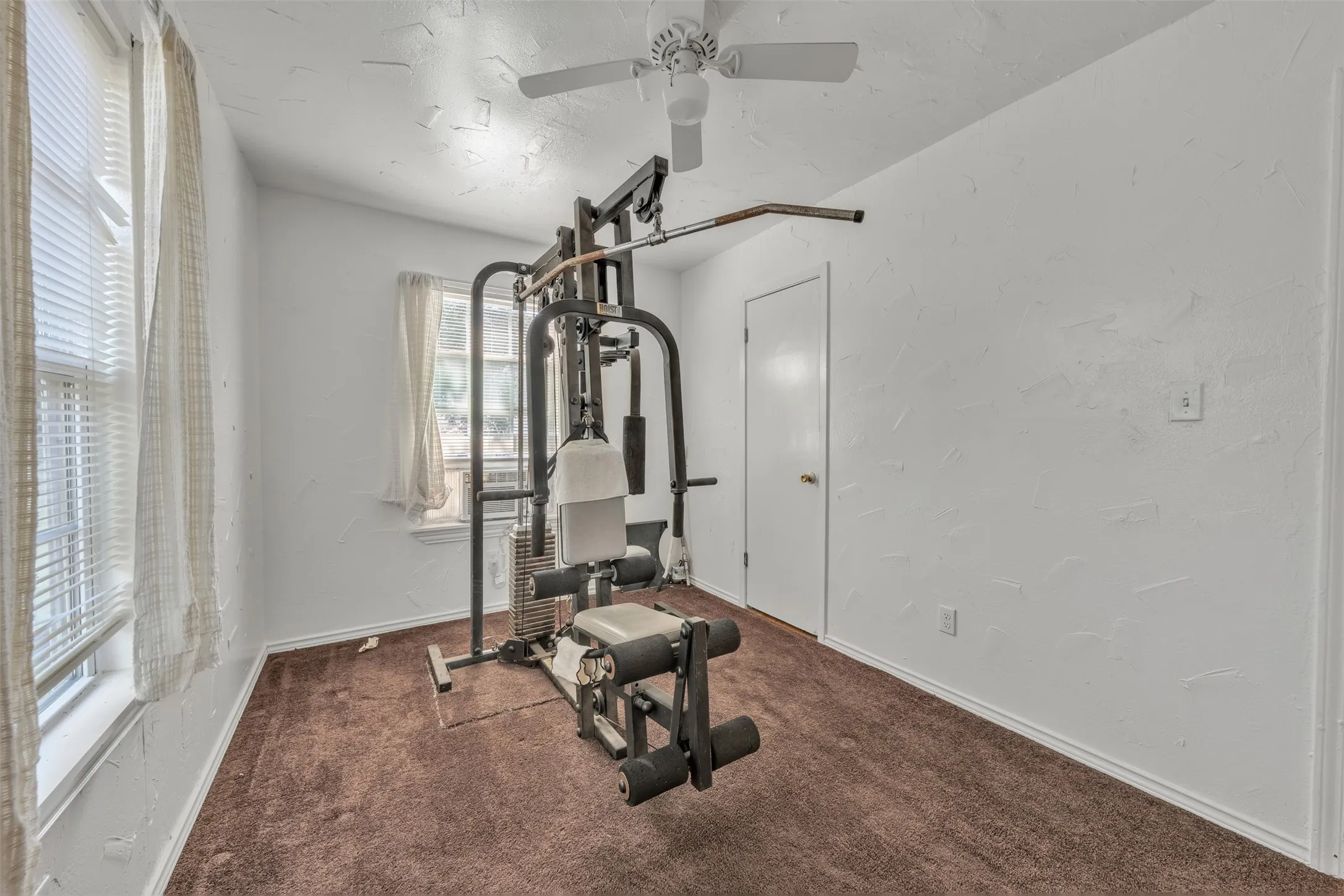 Room featuring textured white walls, brown carpet, and white trim