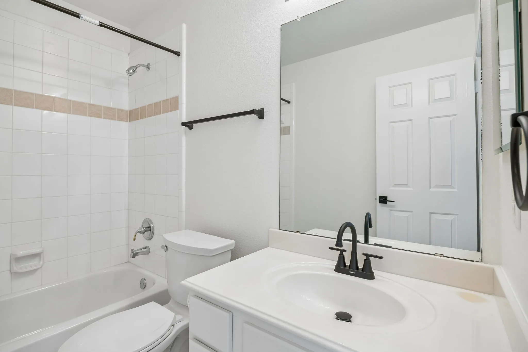 Bathroom featuring a white vanity with an integrated sink, matte black faucet, and a large unframed mirror