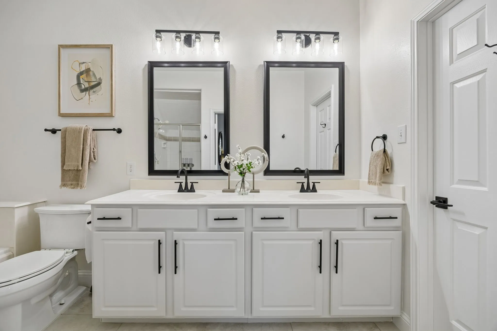 Double vanity with white cabinetry and integrated sinks, complemented by matte black hardware and fixtures