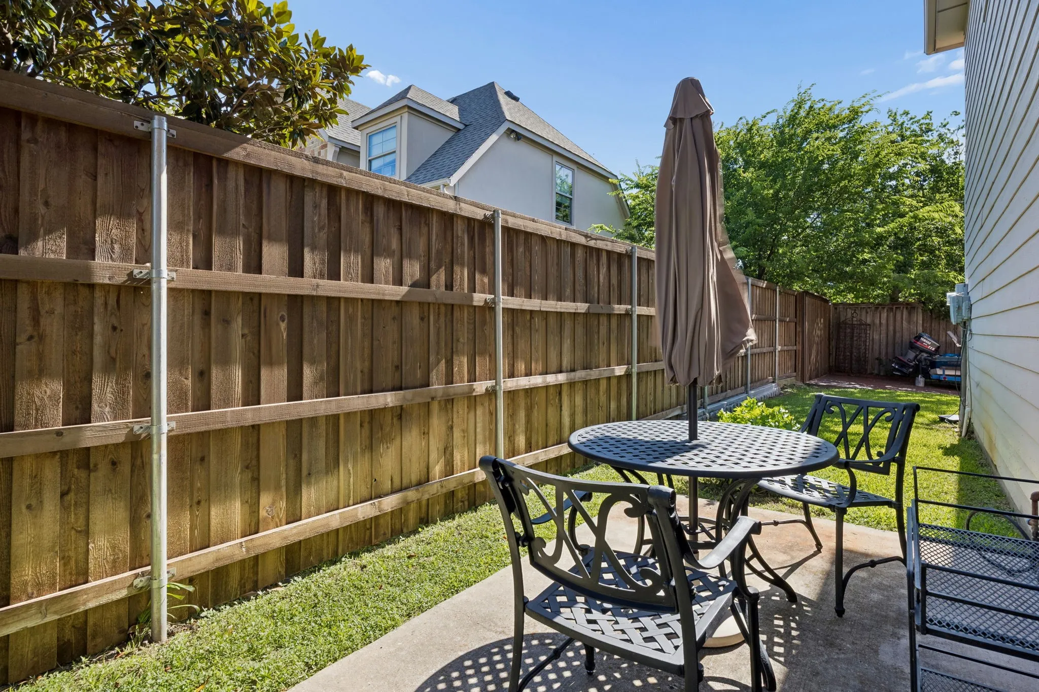 Private backyard featuring a concrete patio, wood fencing, and a grassy area